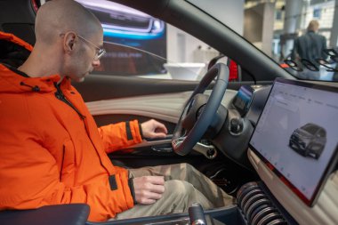 Genç adam inceler, yeni kırmızı BYD ATTO 3 Car 'ı seçer, direksiyon başında Çinli BYD üreticisi, test sürücüsü, otomotiv endüstrisi, Frankfurt, Almanya - 31 Ocak 2024