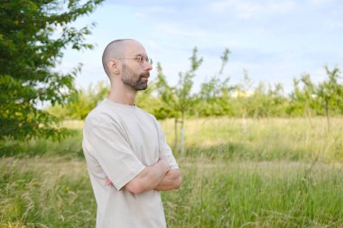 30-35 yaşlarında, açık tişörtlü, şık gözlüklü, doğal arka planda, Gençlik Kültürü ve Stereotipli, genç nesil, giysiler, aksesuarlar, açık hava aktiviteleri...