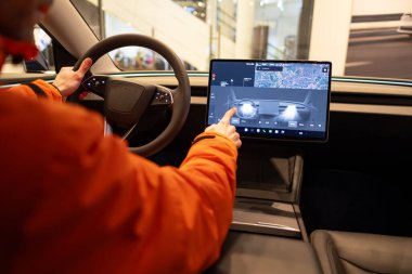 Yakın çekimde erkek eller, test sürüşü sırasında direksiyon simidi Tesla modeli Y elektrikli otomobili kullanır, arabaları test eder ve değerlendirmesini potansiyel alıcılar, Berlin, Almanya - 17 Şubat 2024