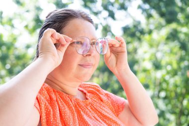 50-55 yaşlarında bir kadın mesafeye bakar, zayıf görür, şaşı olur, gözlük takar, olgun kadın yüzünü, miyopluğu, görüş düzeltmesini kapatır.