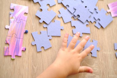 Küçük çocuk bulmacaları birleştiriyor, karton parçaları şekillendiriyor, bulmacaları birleştiriyor, bulmacaları çözerek bilişsel gelişimi sağlıyor.