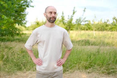 30-35 yaşlarında, açık tişörtlü, şık gözlüklü, doğal arka planda, Gençlik Kültürü ve Stereotipli, genç nesil, giysiler, aksesuarlar, açık hava aktiviteleri...