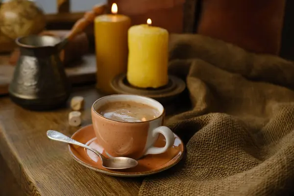 cup with drink coffee on old vintage wooden table, metal coffee maker, candles burn, caffeine improves functioning of human brain, stimulates nervous system, health benefits and harms, copy space