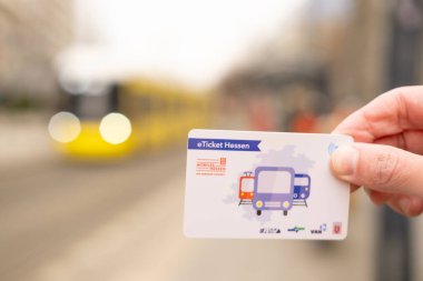 male hand hold electronic Deutschland-Ticket, yellow tram Flexity Berlin driving down city street in Berlin, monthly travel pass in germany for public transport, Berlin, Germany - February 19, 2024 clipart
