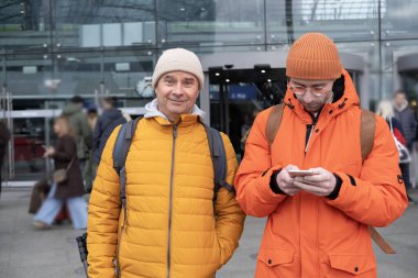 İstasyonda turuncu ceketli iki adam, sırt çantalı yolcular Berlin Hauptbahnhof istasyonunda treni bekliyorlar, konsept yolcuları, hızlı ve hızlı tren yolculuğu, Berlin, Almanya