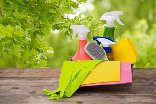 Корзина с чистящими средствами на размытом весеннем фоне, весенняя уборка дома, салфетки, моющие средства, экологически чистые и экологичные чистящие средства