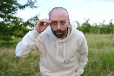 30 yaşında, gözlüklü sakallı bir genç. Gözlüklü. Şaşırtıcı bir şekilde merceğe bakıyor.