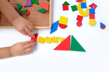 Akıllı küçük çocuk, kız 3 yaşında eğitici oyuncaklar, tahta geometrik figürler, tahta bulmacalar, çocuk elleri renkli ahşap geometrik şekillerden resimler yaratıyor.