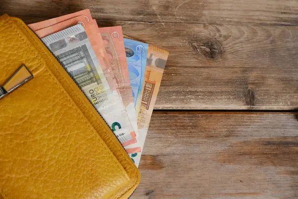 yellow leather wallet with EU banknotes, cash money on wooden table, finances in business and entrepreneurship concept, skillful personal finance management