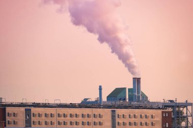 Bacadan çıkan buharlı dramatik manzara fabrikası, gün batımına doğru yükseliyor, gücü ve endüstriyi yakalıyor, sanayileşmenin çevresel etkisi, modern dünyanın sürdürülebilir uygulamaları,