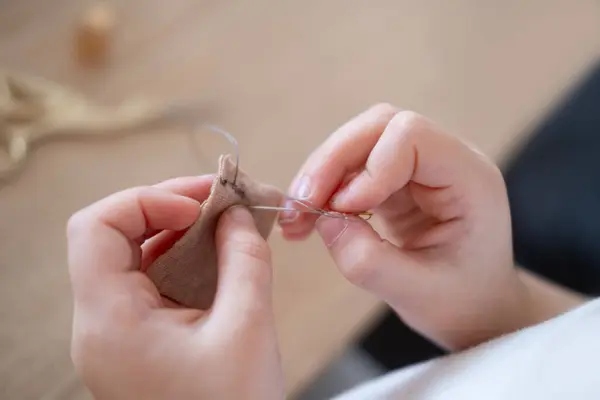 Close-up child\'s hands carefully stitching doll\'s dress, highlighting fine motor skills and creativity involved, fine motor skills, hands-on activity, creative activity