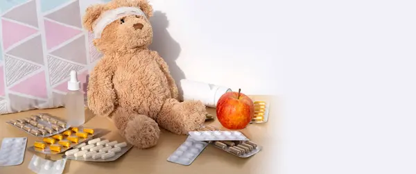 teddy bear with bandaged head, surrounded by scattered medicines and pills, health, care and treatment children through soft toy, medical therapy and pediatrics
