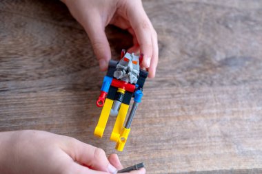 Yakın plan çocuk elleri parçalardan inşaat yaratıyor, robot dağcı figürü, mühendislik eğitimi, oyun yoluyla öğrenme, yaratıcılığın gelişimi, iyi motor beceriler