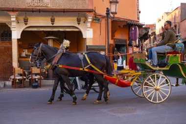 Marakeş turistleri ve yerliler, geleneksel at arabalarıyla, Marakeş 'in Ebedi Cazibesi, Marakeş, Fas - 3 Ocak 2024