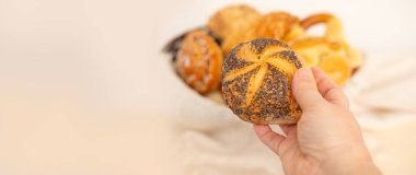 Çeşitli renkte pastalar, ekmek ürünleri, fırın, çörekler, peynir ve haşhaş tohumu ruloları, krakerler ve süzme peynirli turtalar dokuma sepetinde sergilenmektedir.