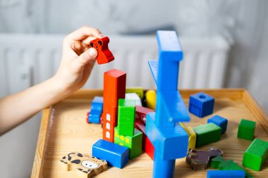 Akıllı çocuk, eğitim oyuncağıyla oynayan okul çocuğu, tahtadan geometrik figürler, çocuğun elindeki bloklar, beyin oyunları, konsept çocukluğu, çocuk gelişimi, yaratıcılık