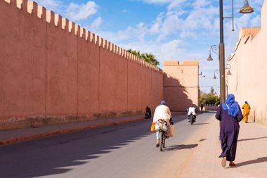 İnsanlar yüksek duvar boyunca yürür Red City Marakeş iş, otantik Afrika manzarası, günlük aktiviteler ve şehirde yaşayan insanlarla etkileşimler hakkında acele