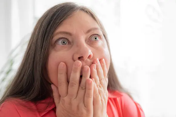 stock image mature scared woman with bulging eyes, face close-up, goggle eyes in fright, staring in waking nightmare, Very strong surprise or shock, fright, universal horror in look