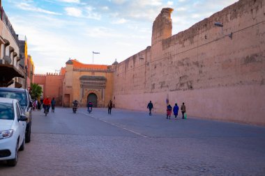 İnsanlar yüksek duvar boyunca yürüyorlar Kızıl Şehir Marakeş acele iş, otantik Afrika manzarası, günlük aktiviteler ve etkileşimler hakkında Marakeş, Fas 'ta yaşayan insanlar - 7 Ocak 2024