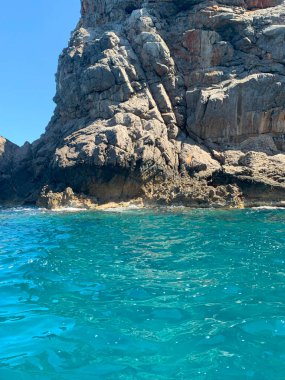 Gök mavisi denizdeki dağlık kayalık ada, durgun su denizi, güneşli günde macera, harika tatil, açık hava aktiviteleri.,