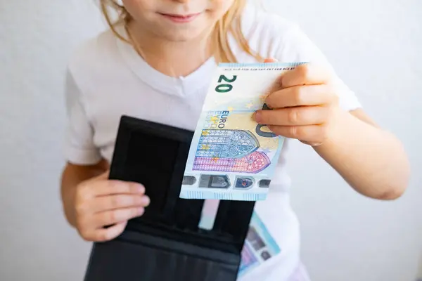 child holds black wallet in hand, kid, girl secretly takes money out of parents\' wallet, pulls out euro banknotes, concept of pocket money, Personal Boundaries and Trust, Teaching Financial Literacy
