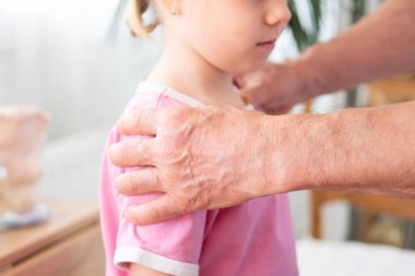 Erkek ortopedist doktor omurilik muayenesi yapar. Küçük kız omurga eğriliği, omurga bozukluğu, sağlık hizmetleri sağlayıcısı, omurga kontrolü, sağlık kontrolü, omurilik muayenesi yapar.