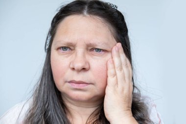 Hastalıklı olgun bir kadın şiddetli baş ağrısı yaşar, başını tutar, menopoz sırasında sıcak basması, hafıza ve konsantrasyonda azalma, gergin, yorgun, bitkin, menopoz geçirir.