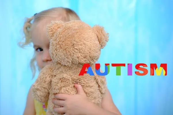 Otizmli küçük bir çocuk, sarışın bir kız 3 yaşında oyuncakla oynuyor, oyuncak ayıya sarılıyor, otistik insanlara destek oluyor, kendini kabulleniyor ve nöroçeşitliliği kucaklıyor.