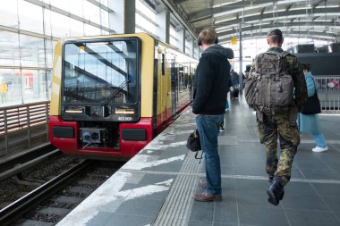 Deutsche Bahn bölgesel treni Berlin istasyonuna ulaşır. Platformda bekleyen yolcular, toplu taşıma gecikmesi, günlük ulaşım, Berlin - 25 Nisan 2024