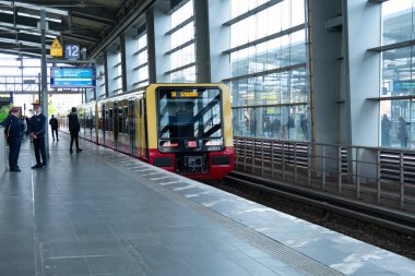 Deutsche Bahn bölgesel treni Berlin istasyonuna ulaşır. Platformda bekleyen yolcular, toplu taşıma gecikmesi, günlük ulaşım, Berlin - 25 Nisan 2024