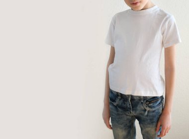 Çocuğun bir parçası, beyaz tişörtlü 10 yaşındaki bir çocuk, iyi duruş, çocuklukta skolyozun önlenmesi, işitme sağlığı konsepti, mutlu çocukluk, tasarımcı mokasyonu