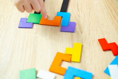 Bebek elleri rengarenk ahşap geometrik parçaları manipüle eder. Entelektüel bulmacalar, akıllı çocuk sorunları çözer. Beyin gelişimi, ince motor beceriler.