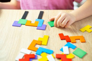 Evinde tahta bloklarla oynayan 5 yaşındaki küçük bir kız, çocuk eli karmaşık dünyayı keşfediyor renkli ahşap yapboz, yaratıcılığı besliyor, hayal gücünü geliştiriyor.