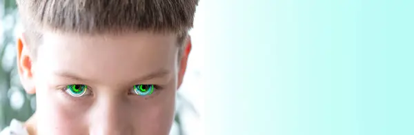 stock image close-up bionic eyes, caucasian child, aggressive boy looking sideways, intense stare, determined to get their way