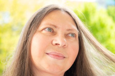 Beyaz tenli, 50 yaşında, çekici, uzun saçlı, zarif bir kadın. Yüzü güzel. Yakın portre, yaşlanma karşıtı bakım prosedürleri.