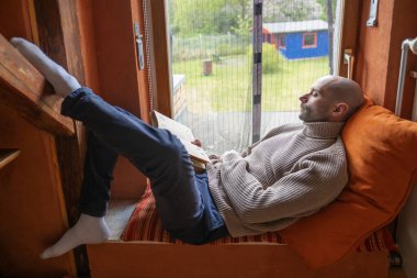 Genç adam ilginç eski bir kitap okurken uyuyakalmış, düşüncelere dalmış, dünya kitaplarına kaçıyor, büyüleyici bir hikayeyle eski pencere pervazına kurulmuş, tavan arası pencere pervazına.