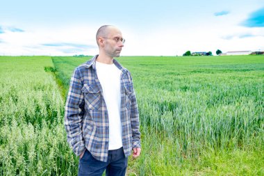 Genç adam yeşil yulaf tarlalarında, doğanın tadını çıkarıyor, çiftçinin gururu, tarım arazisi, yeşil doğa aktivitesi, doğanın kucaklaması.