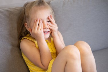 tatlı çocuk, utangaç sarışın kız elleri ile gözleri örtüyor, neşeli masumiyet, duygusal ifade, hassas an, çocukluk cazibesi