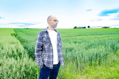 Genç adam yeşil yulaf tarlalarında, doğanın tadını çıkarıyor, çiftçinin gururu, tarım arazisi, yeşil doğa aktivitesi, doğanın kucaklaması.