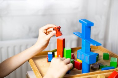 Akıllı çocuk, eğitim oyuncağıyla oynayan okul çocuğu, tahtadan geometrik figürler, çocuğun elindeki bloklar, beyin oyunları, konsept çocukluğu, çocuk gelişimi, yaratıcılık