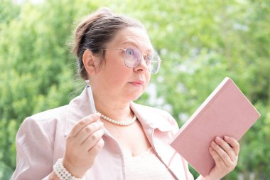 Olgun iş kadını, 50 'li yaşlarda pembe ceketli, planlamacı çok şaşırmış, profesyonel hedefler ve kişisel refah arasında denge var.