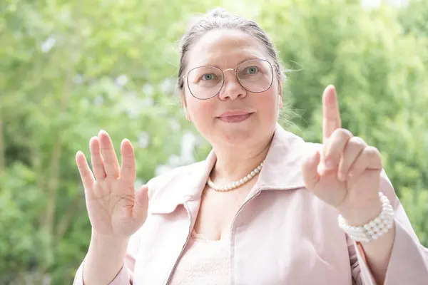 stock image mature businesswoman in glasses, elegant independent woman 50 years old in pink blazer pointing finger, balance between professional goals and personal well-being