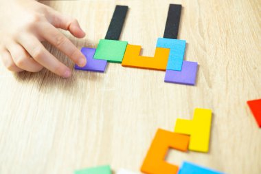 Akıllı çocuk problemi çözer, renkli ahşap geometrik parçaları manipüle eder. Entelektüel bulmaca, bilişsel büyüme, zeka oyunu, düşünme becerileri.