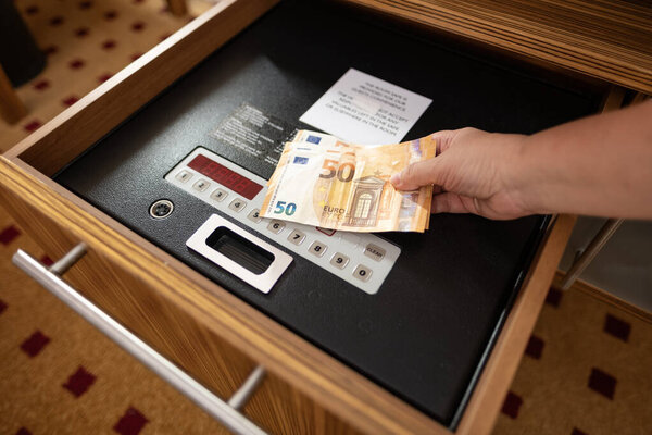 женщина размещает стек 50 евро банкноты в безопасный отель электронный сейф, путешествия финансы обрабатываются безопасно, сейф отеля безопасности путешественника сейф