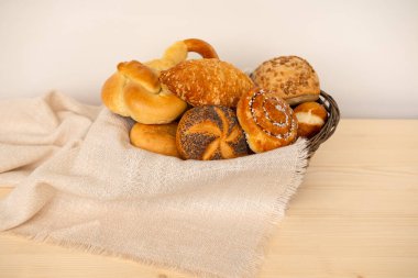 Peynirli çörekler, haşhaşlı çörekler, rulo ekmekler, tuzlu krakerler ve geleneksel hasır sepetinde tatlı kaymaklı tartlar içeren lezzetli ev yapımı hamur işleri.