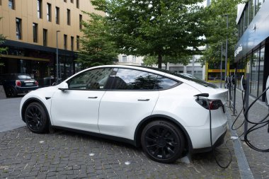 beyaz Tesla Model araba caddede şarj oluyor, yenilikçi elektrikli araba Tesla Motors, çağdaş Avrupa 'da EV trendi, sürdürülebilir ulaşım, otomotiv endüstrisi, Frankfurt, Almanya - 28 Haziran 2024
