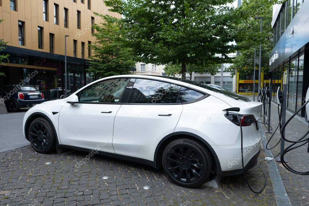 White Tesla Model y car charging on street, innovative electric car Tesla Motors, trend EV in contemporary Europe, sustainable transportation, Automotive industry, Frankfurt, Germany - June 28, 2024