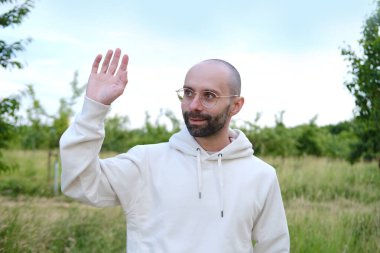 30 yaşındaki genç sakallı adam gülümseyerek manzaranın tadını çıkarıyor, el ele selamlaşma, doğa ve maceranın tadını çıkarma, temiz havanın, doğal güzelliğin, açık hava hayatının tadını çıkarma,