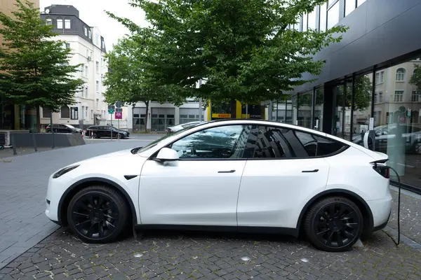 stock image white Tesla Model y car charging on street, innovative electric car Tesla Motors, trend EV in contemporary Europe, sustainable transportation, Automotive industry, Frankfurt, Germany - June 28, 2024