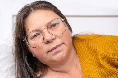 yorgun, ciddi, olgun, 50 yaşında, uzun saçlı, sarı kazaklı, gözlüklü, yakın çekim yüzü, ruh hali ve duyguları olan, Psikolojik Görünüm ve Uygulamalar, Modern Dünya Kadın Sağlığı